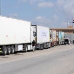 Camiones de un convoy de ayuda humanitaria estacionados frente a la puerta fronteriza entre Egipto y Gaza, en Rafah