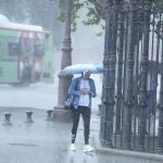 Una mujer camina bajo la lluvia por Sevilla