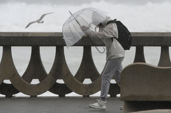 Una persona se protege de la lluvia y el viento con un paraguas, en A Coruña, Galicia. Imagen de archivo