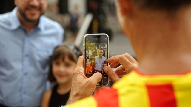 Un hombre con la camiseta del Barça fotografía al presidente de la Generalitat, Pere Aragonès, con dos niños