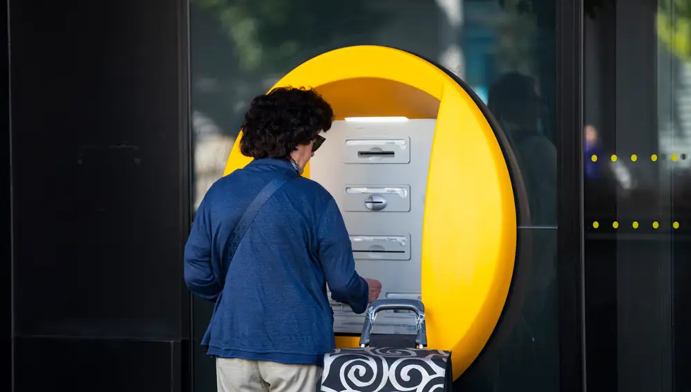 Una mujer saca dinero de un cajero