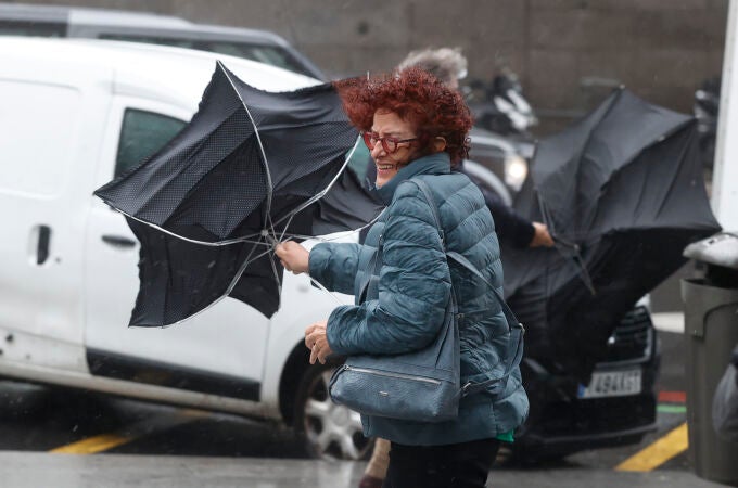 Una viandante se enfrenta a las fuertes rachas de viento mientras camina por una calle del centro de Madrid