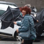 Una viandante se enfrenta a las fuertes rachas de viento mientras camina por una calle del centro de Madrid