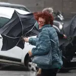 Una viandante se enfrenta a las fuertes rachas de viento mientras camina por una calle del centro de Madrid