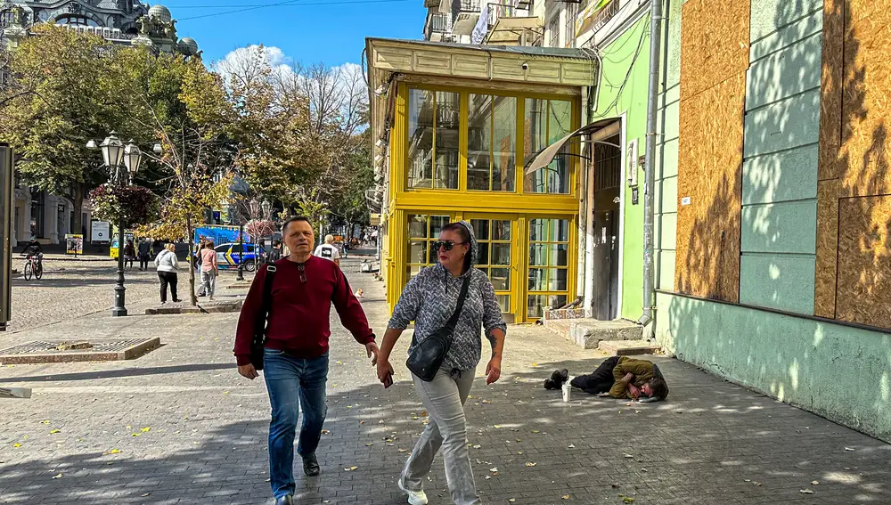 Dos personas caminan junto a un mendigo en Odesa