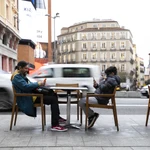 Imagen de un adulto y un niño viendo el teléfono movil en una terraza de Madrid.