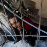 Palestinos buscan supervivientes bajo los escombros de un edificio destruido tras un ataque aéreo israelí en el campo de refugiados de Jan Yunis