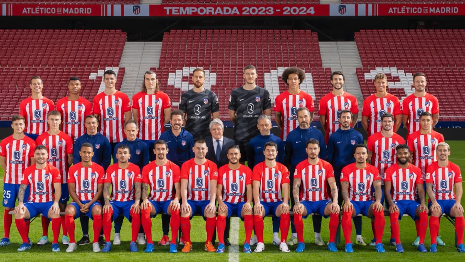 Dos aficionados posan con los jugadores del Atlético de Madrid 23-24 en la foto oficial