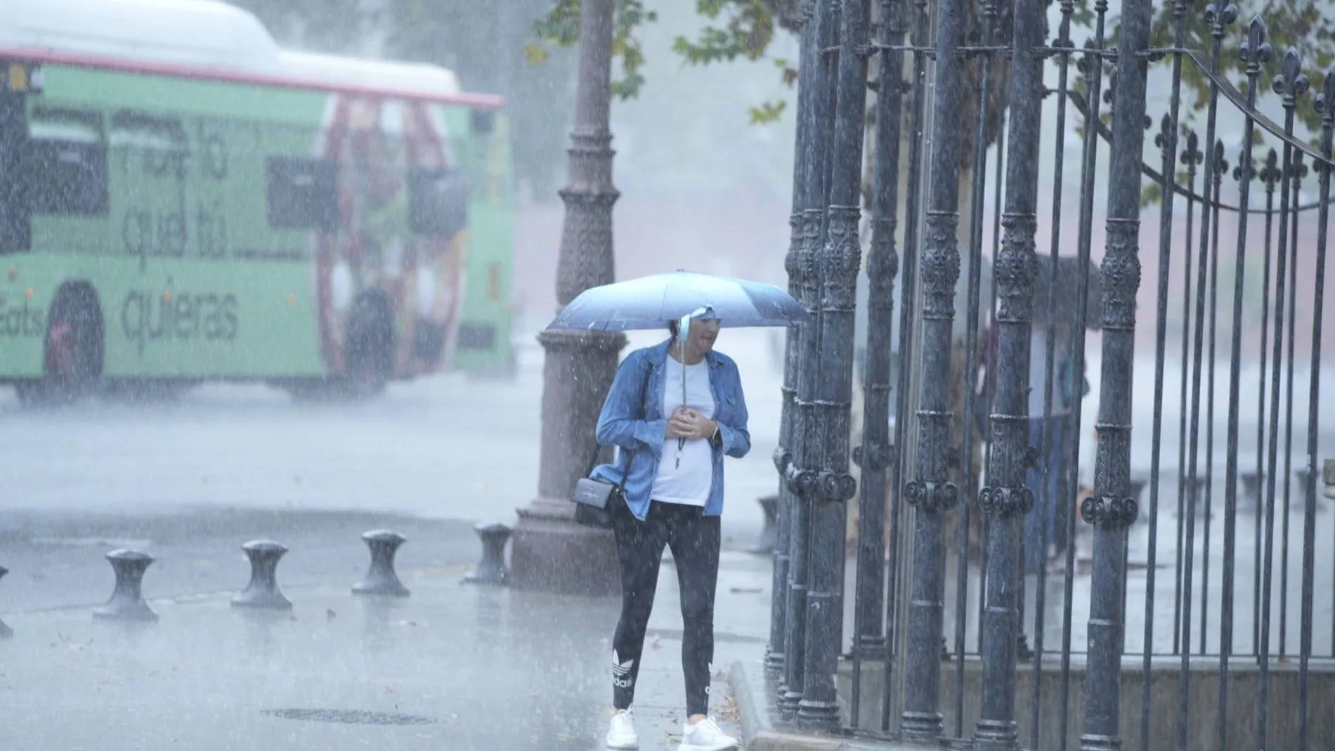 Una mujer se resguarda de la lluvia bajo un paragüas