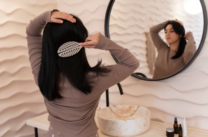 Una mujer cepillándose el pelo tras utilizar productos para el cabello