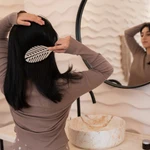 Una mujer cepillándose el pelo tras utilizar productos para el cabello