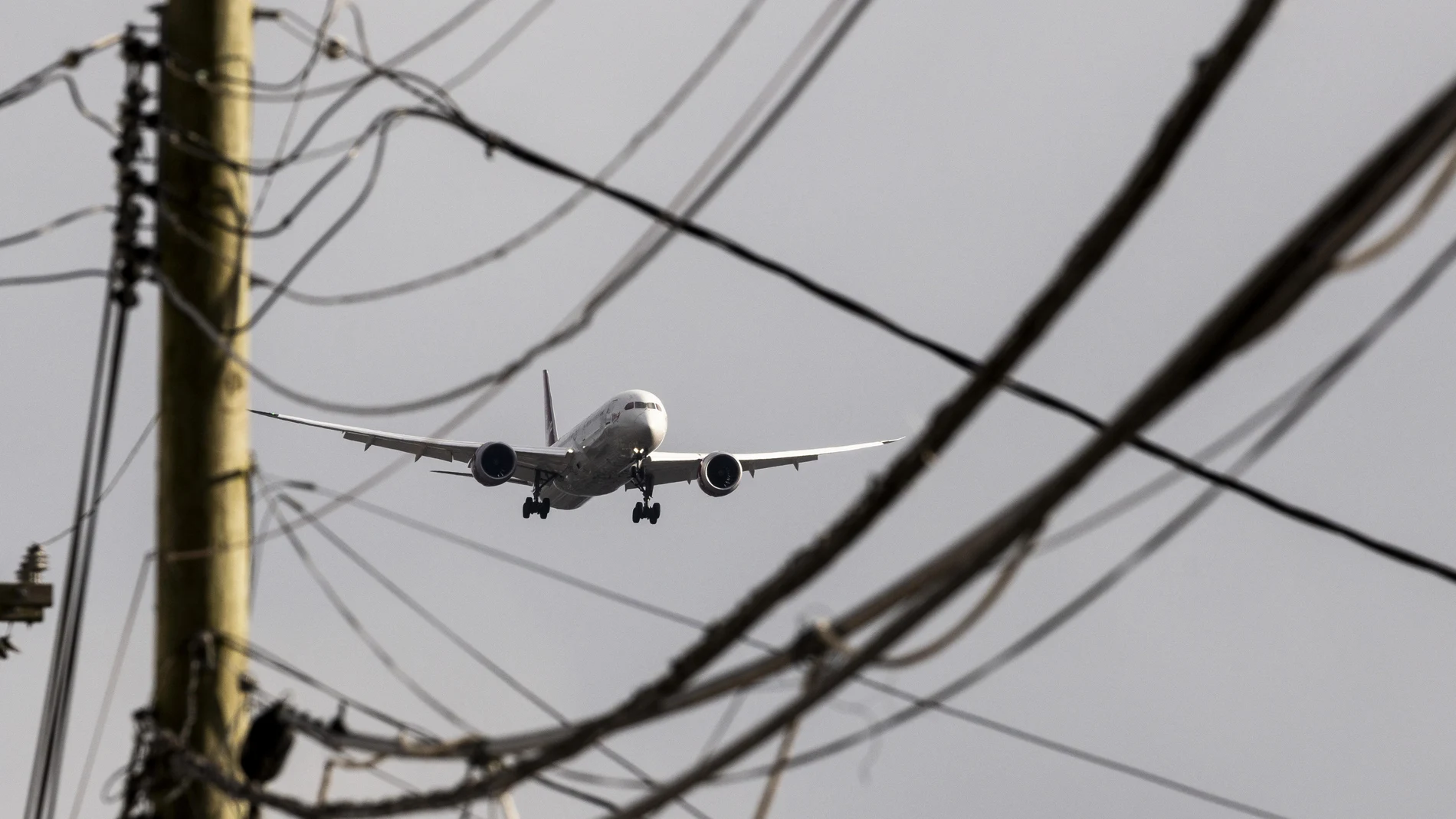 Seen through power lines, Virgin Atlantic's Flight100, the first commercial airplane to make a transatlantic flight with 100 percent Sustainable Aviation Fuel (SAF), on approach to John F. Kennedy International Airport in New York, New York, 28 November 2023. 