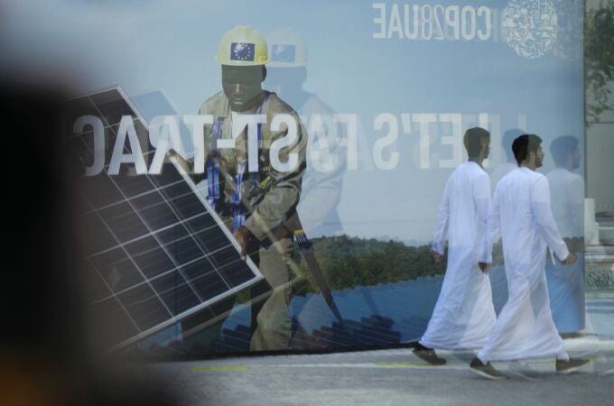 People walk near a sign for the COP28 U.N. Climate Summit, Tuesday, Nov. 28, 2023, in Dubai, United Arab Emirates. (AP Photo/Peter Dejong)