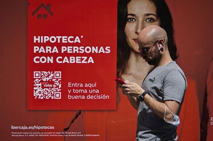 Una oficina de un banco con publicidad de hipotecas en su fachada.