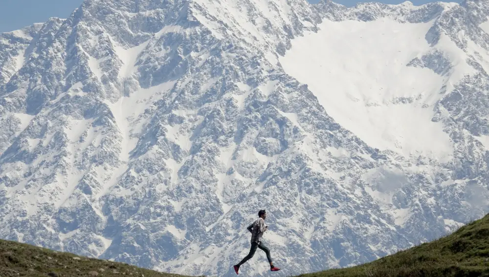 Una persona corre frente a la cordillera de Dhauladhar en la aldea de Jalot, Himachal Pradesh, India, el 22 de abril de 2020. La cordillera de Dhauladhar es parte de la cadena menor de montañas del Himalaya, siendo Hanuman Tibb el pico más alto con casi 6,000 metros. 