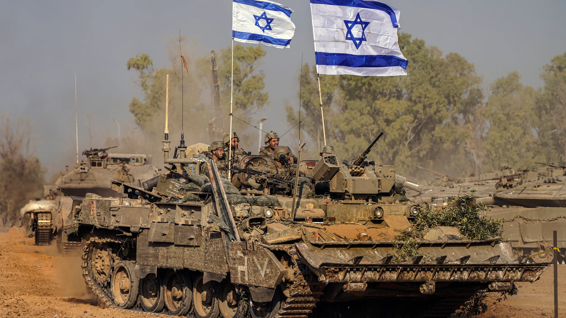 Israeli army vehicles arrive to an staging area after combat in the Gaza Strip in southern Israel, Saturday, Dec. 30, 2023. The army is battling Palestinian militants across Gaza in the war ignited by Hamas' Oct. 7 attack into Israel. (AP Photo/Tsafrir Abayov)
