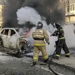 A handout photo made available by the Russian Emergency Ministry press service shows Russian firefighters extinguishing a burning car after shelling in Belgorod, Russia, 30 December 2023. 12 adults and two children were killed due to shelling by the Ukrainian Armed Forces, the press service of the Russian Ministry of Emergency Situations reported 30 December. 