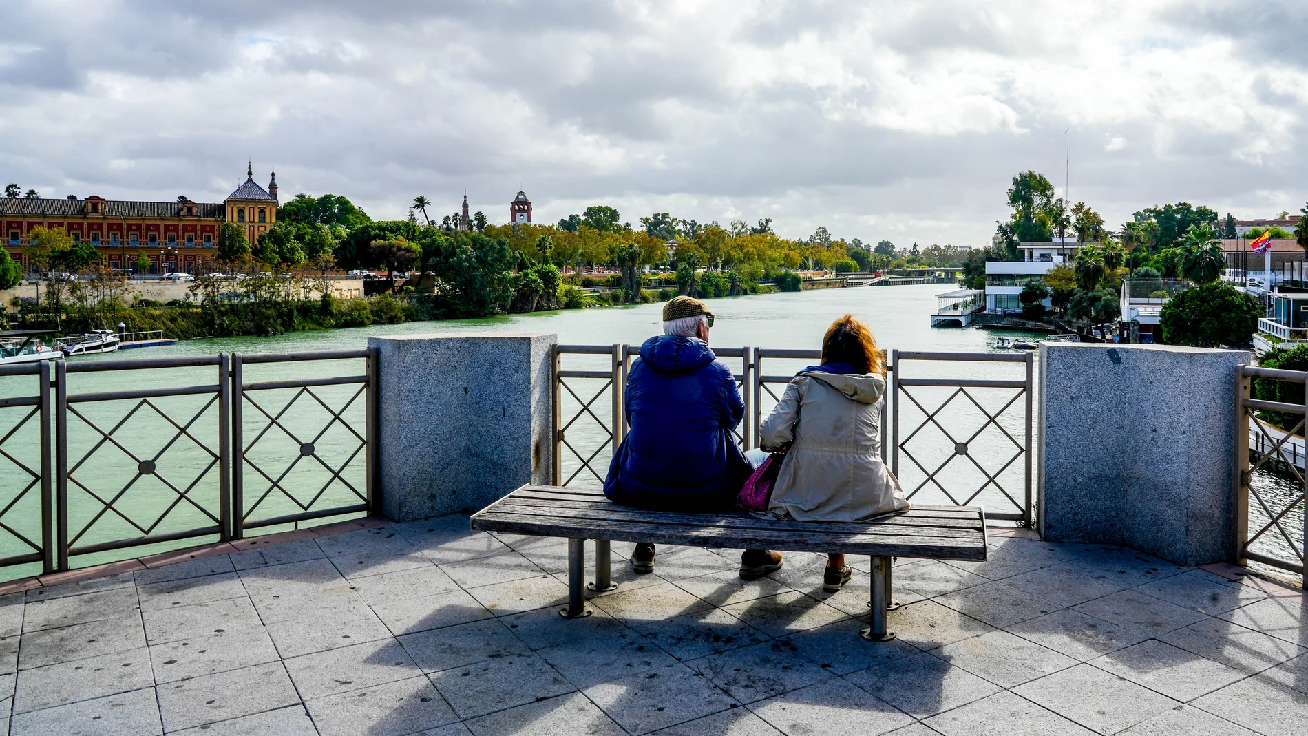 Una pareja de anciano sentados en un banco del Puente de San Telmo.