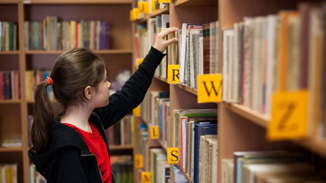 Estudiante consulta una biblioteca de libros de papel