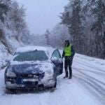 Un agente de la Guardia Civil atiende a un conductor debido a la presencia de nieve en la carretera