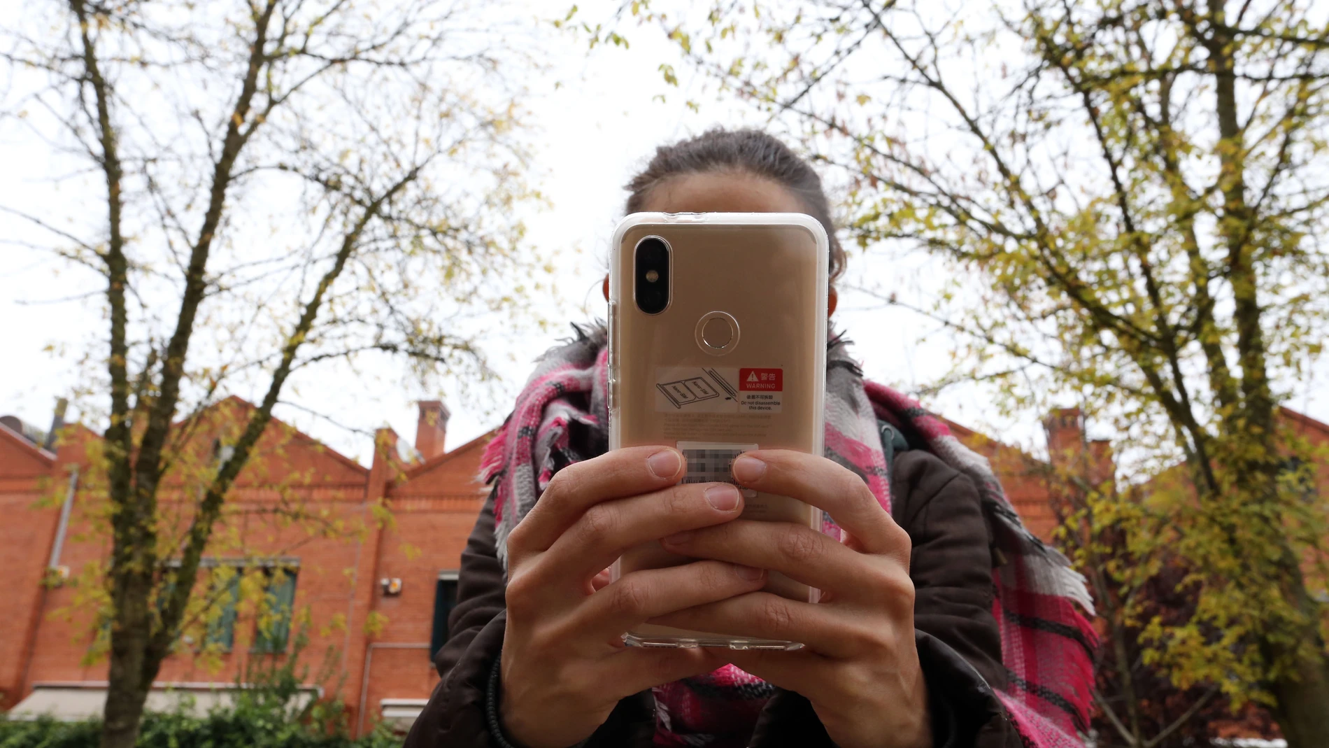 Una joven utiliza un móvil en las cercanías de un Instituto de Valladolid