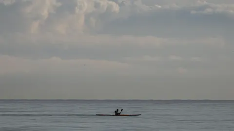 Una persona en la playa de la Malvarrosa hoy, con el cielo nuboso de fondo.