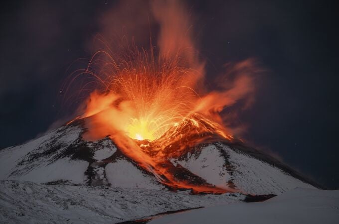 Lava erupts from snow-covered Mt Etna volcano, Sicily, Italy, early Saturday, Nov. 25, 2023. Europe's most active volcano remains active scattering ashes around a vastly populated area on its slopes. (AP Photo/Etnawalk, Giuseppe Di Stefano)