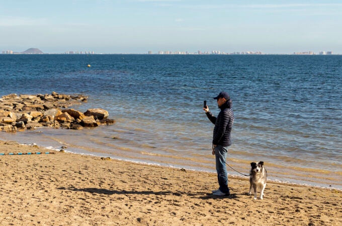 Un hombre pasea a su perro en una playa de Los Alcazares, (Murcia)