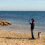Un hombre pasea a su perro en una playa de Los Alcazares, (Murcia)