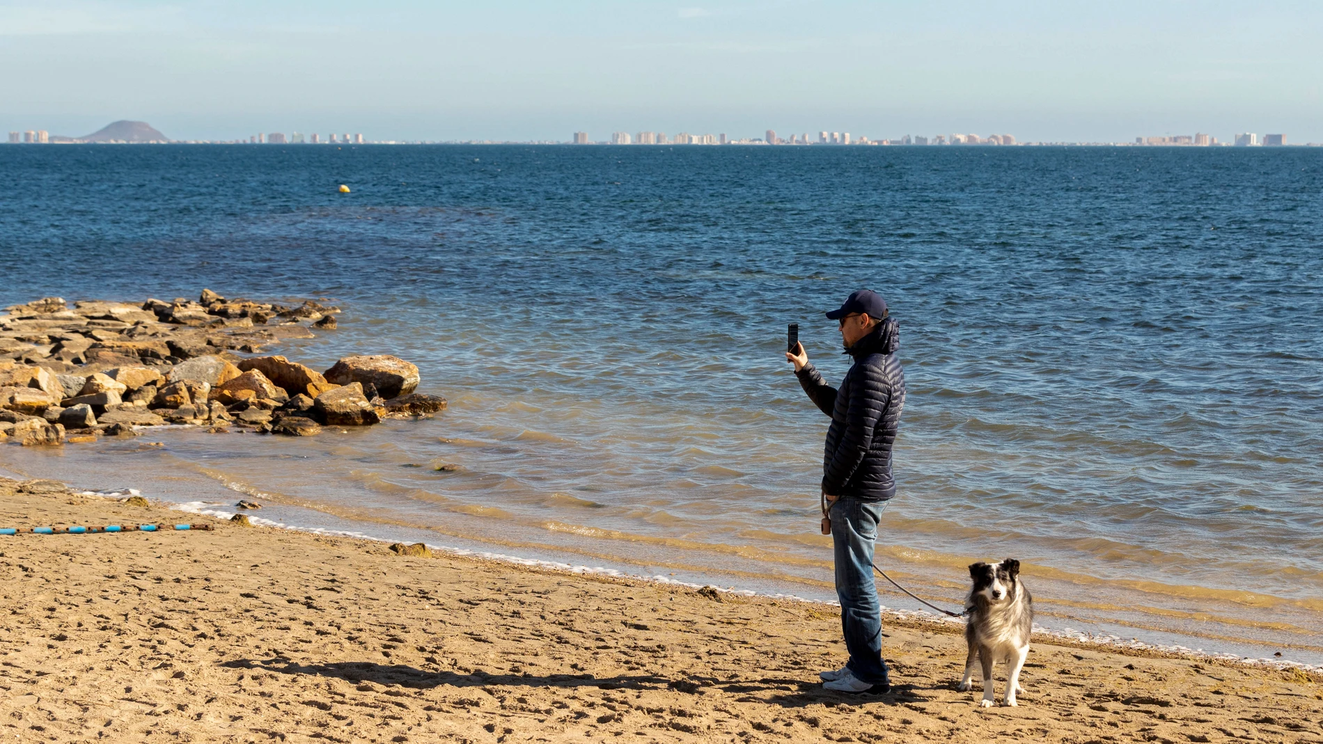 Un hombre pasea a su perro en una playa de Los Alcazares, (Murcia)