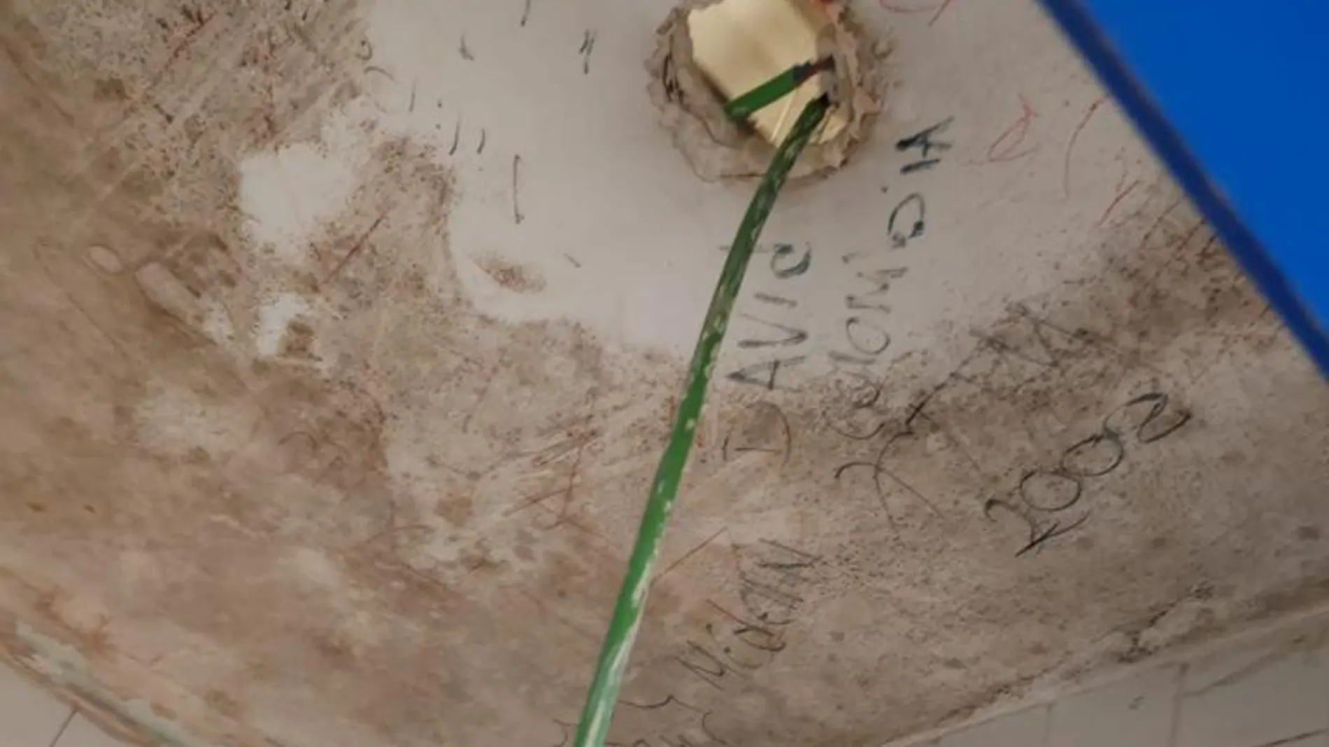 Butrón del falso techo en uno de los baños de las salas donde esperan los asilados.