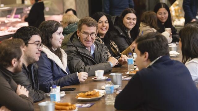 El presidente del PP; Alberto Núñez Feijóo (4i), se reúne con jóvenes en la churrería "La Modernita" en Lugo este viernes.