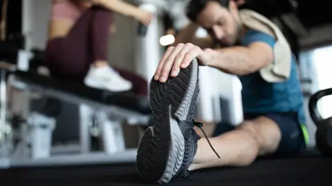 Un hombre realiza estiramientos en un gimnasio