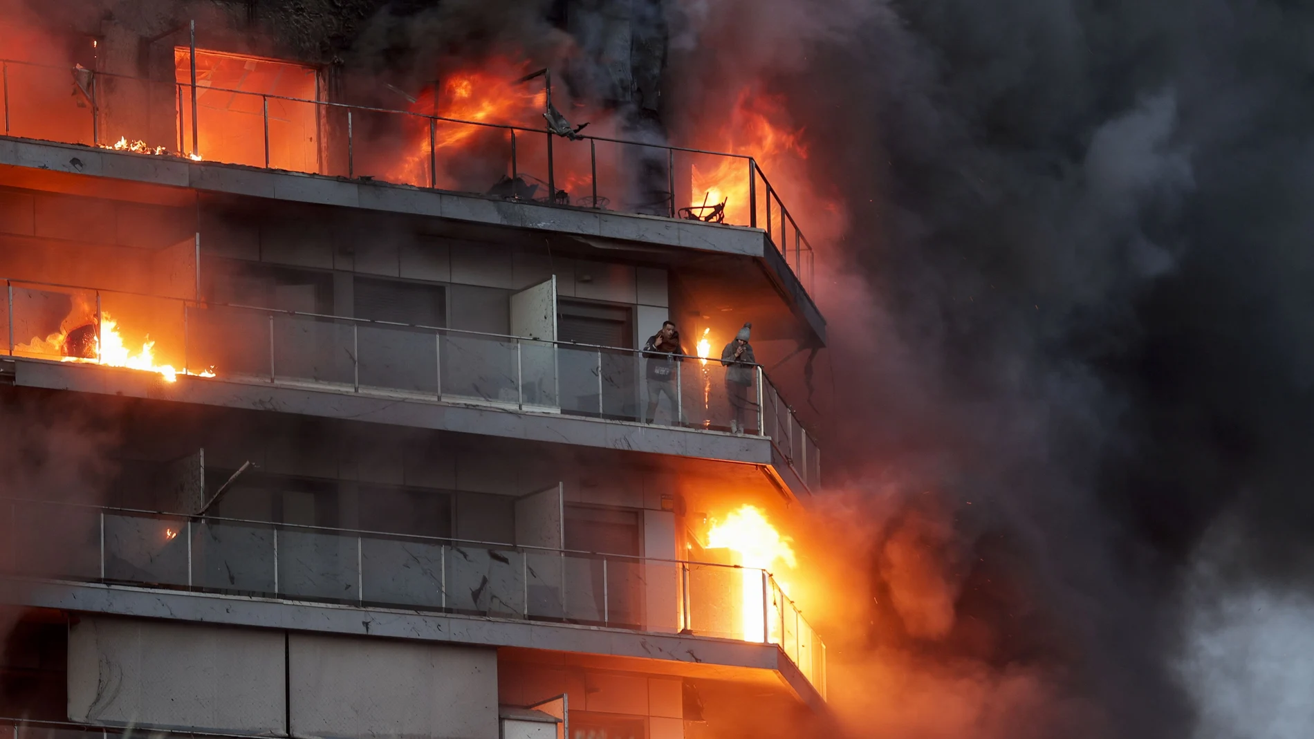 Dos personas aguardan en el balcón a ser rescatadas en el incendio declarado sobre las cinco y media de esta tarde en un quinto piso de un edificio de viviendas de València que ha afectado totalmente al inmueble y se ha propagado a otro anexo, y los bomberos intentan aún rescatar a vecinos desde los balcones. 