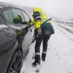 Un agentes de la Guardia Civil auxilia a un vehículo en la Autovía A-6 que se encuentra cubierta de nieve. Carreteras cortadas y cadenas para circular por las nevadas en puertos de montaña del norte especialmente, además de tráfico marítimo suspendido en el Estrecho, olas de 8 metros en el Cantábrico y árboles caídos por la lluvia y el viento son efectos del temporal que un día más mantiene en alerta al país.