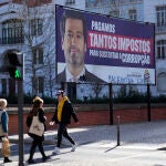 Gente pasa en Lisboa junto a un cartel de Andre Ventura, el líder de la extrema derecha portuguesa