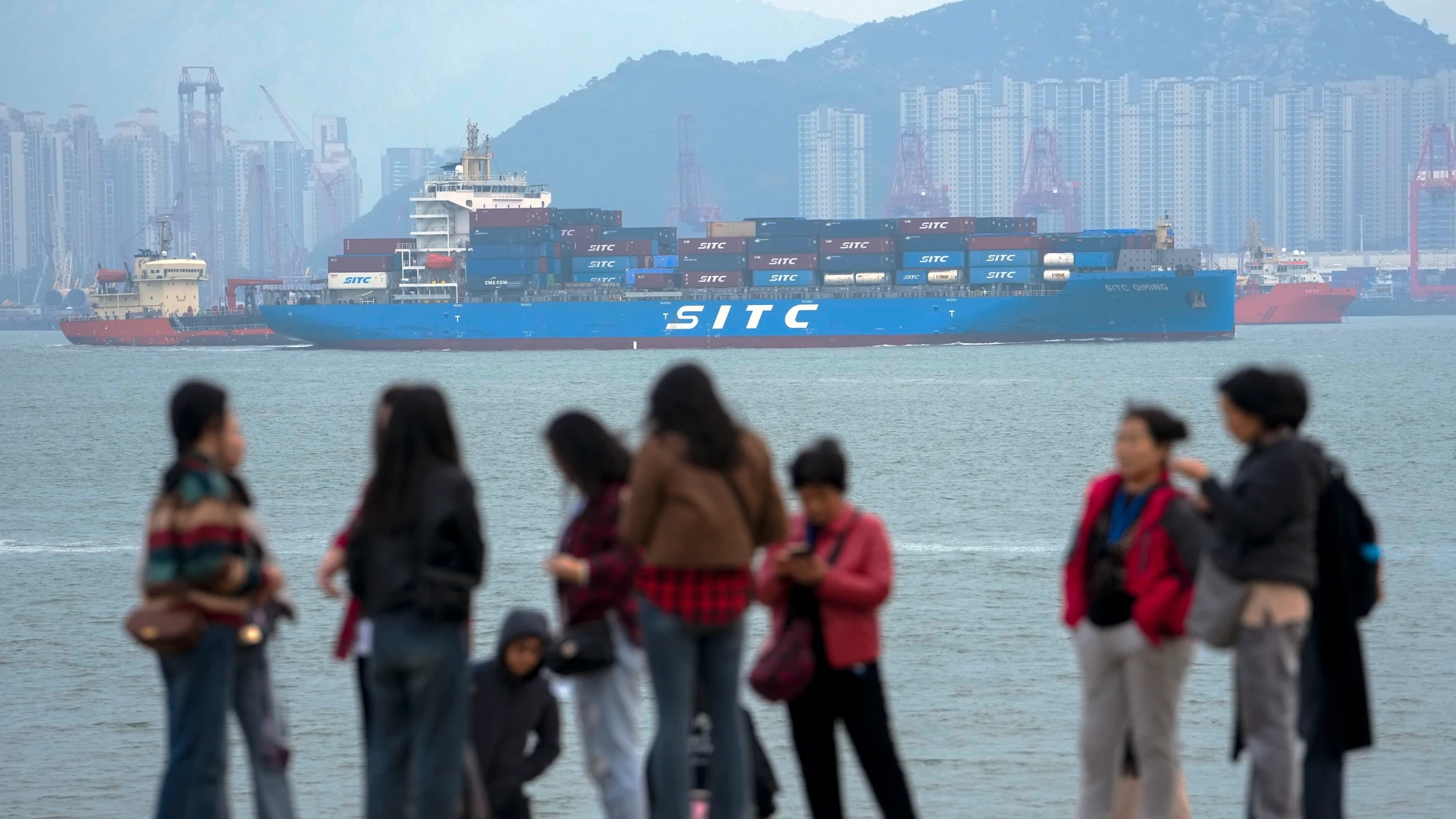 File - A container ship passes tourists in Xiamen in southeast China's Fujian province on Dec. 26, 2023. China’s exports and imports for the January-February period beat estimates, an indication that demand may be improving as Beijing attempts to boost economic recovery, according to customs data released Thursday, March 7, 2024. (AP Photo/Andy Wong, File)