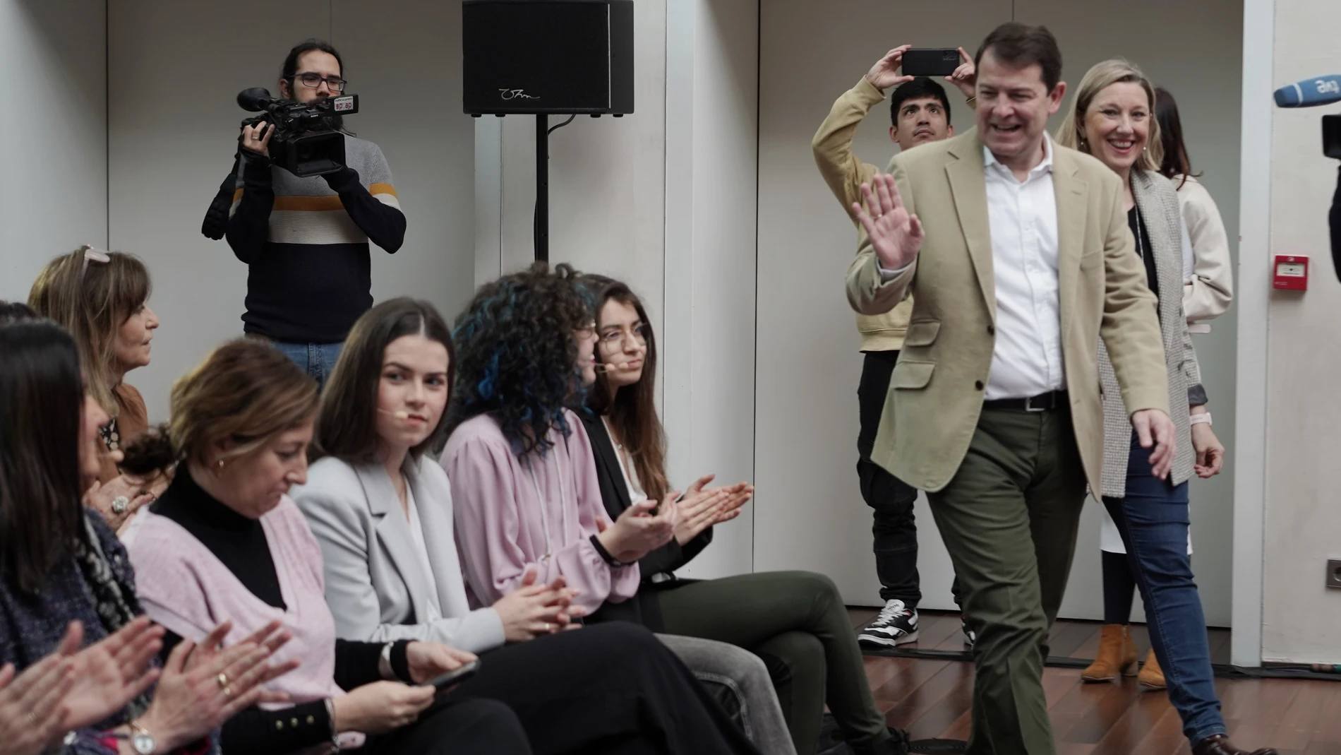 Fernández Mañueco e Isabel Blanco saludan a unas jóvenes en el acto institucional celebrado en Valladolid