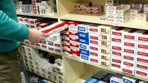 Empleado de un estanco con un cartón de tabaco en la mano