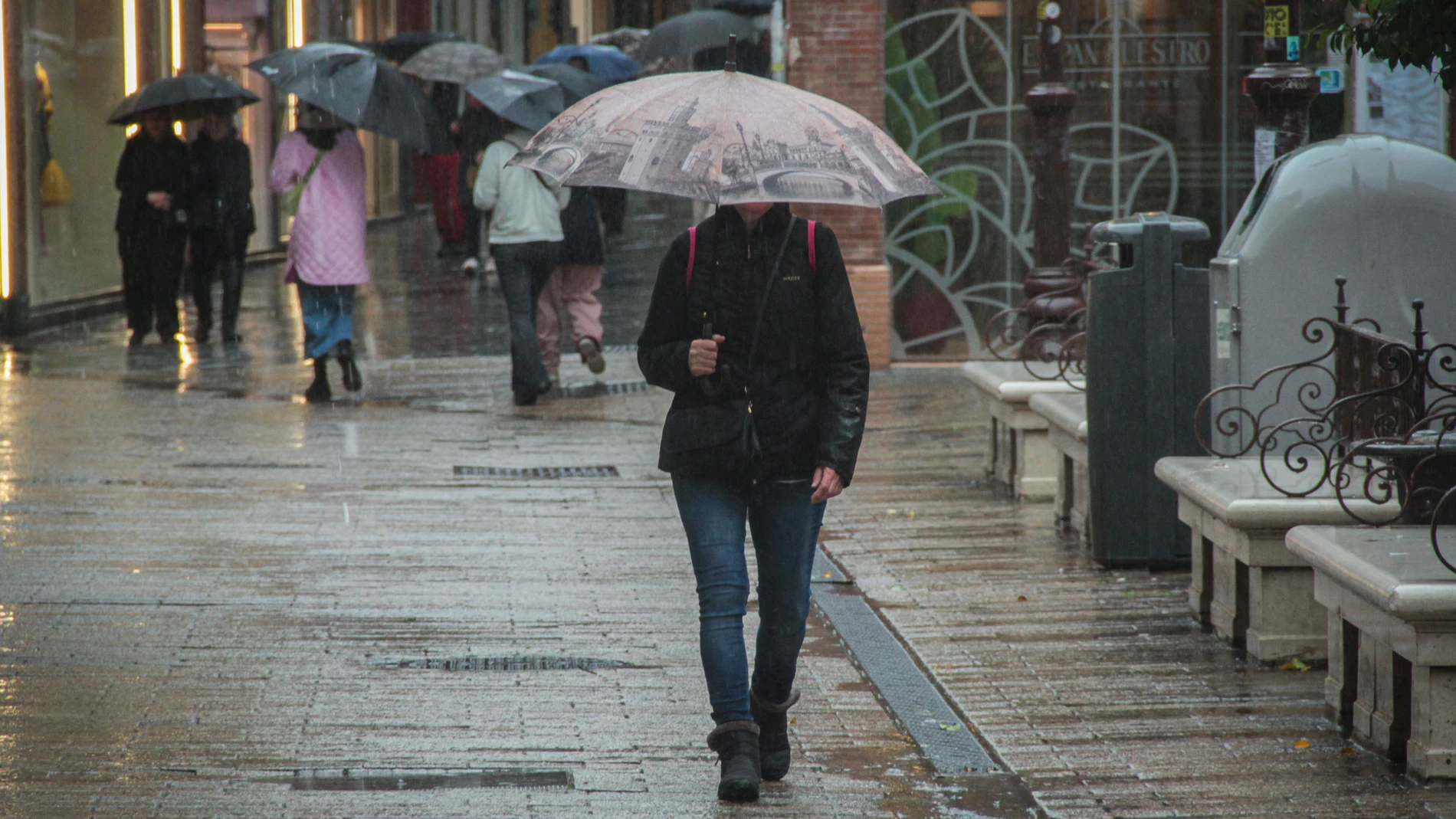 Varias personas pasean bajo la lluvia por el centro de Sevilla