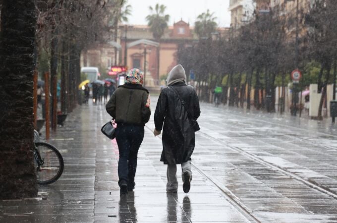 Dos personas pasean por la calle San Fernando de Sevilla bajo la lluvia