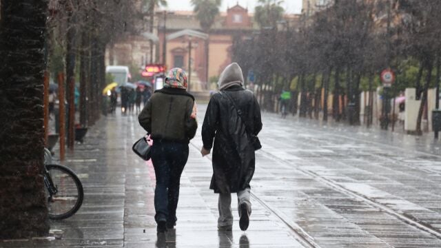 Dos personas pasean por la calle San Fernando de Sevilla bajo la lluvia