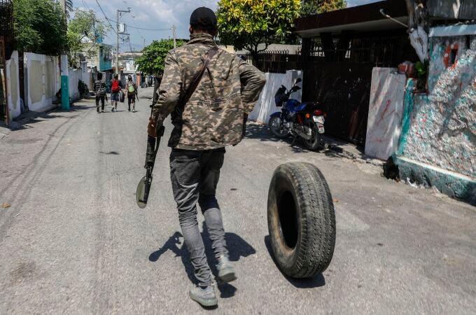 Un hombre armado arrastra un neumático para quemarlo en Puerto Príncipe