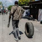 Un hombre armado arrastra un neumático para quemarlo en Puerto Príncipe