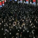 Una gran multitud de gente con mascarilas camina por la estación de Shinagawa en Tokio