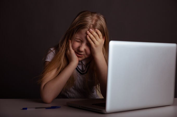 niña con dolor de cabeza delante del ordenador