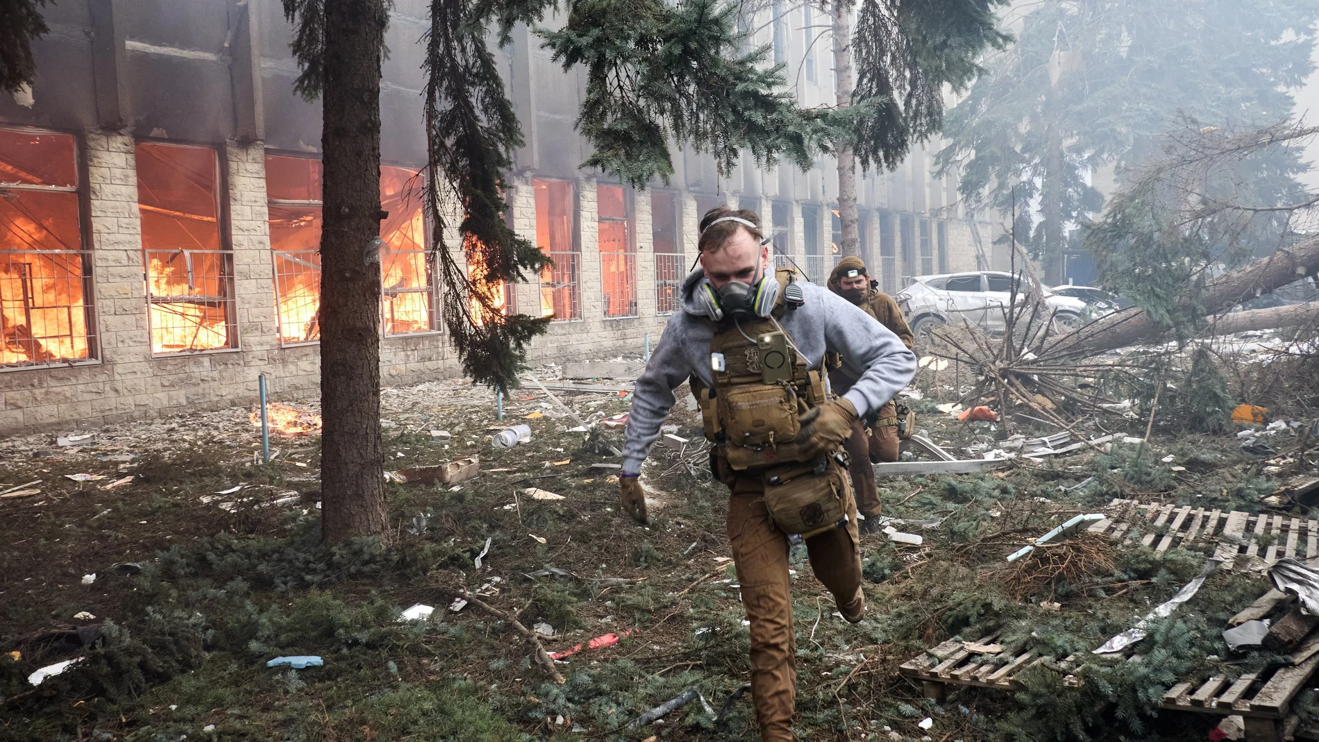 Un militar ucraniano corre en un edificio industrial incendiado en Járkiv