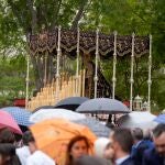 La gente se resguarda de la lluvia mientras ve procesionar a la Hermandad de la Sagrada Cena de Sevilla