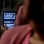 Una mujer con una tablet en la que pone Alphabet Google, a 25 de marzo de 2024, en Madrid (España). Bruselas lanza los tres primeros expedientes sancionadores, en virtud de la nueva Ley de Servicios Digitales, con el objetivo de poner fin al poder monopolístico de las grandes plataformas. 
