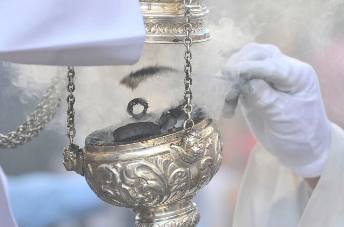 Un acólito recarga un incensario durante un procesión 